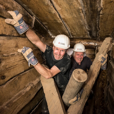 Drei Besucher schauen durch eine Luke im Bergwerk Escape-Room