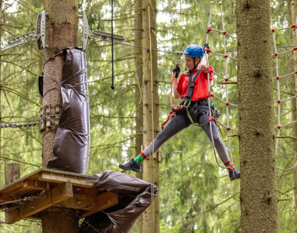 Eine junge Frau zwischen zwei Hindernissen im Kletterpark