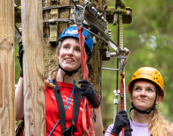 Ein Guide und eine junge Frau in einem Kletterelement